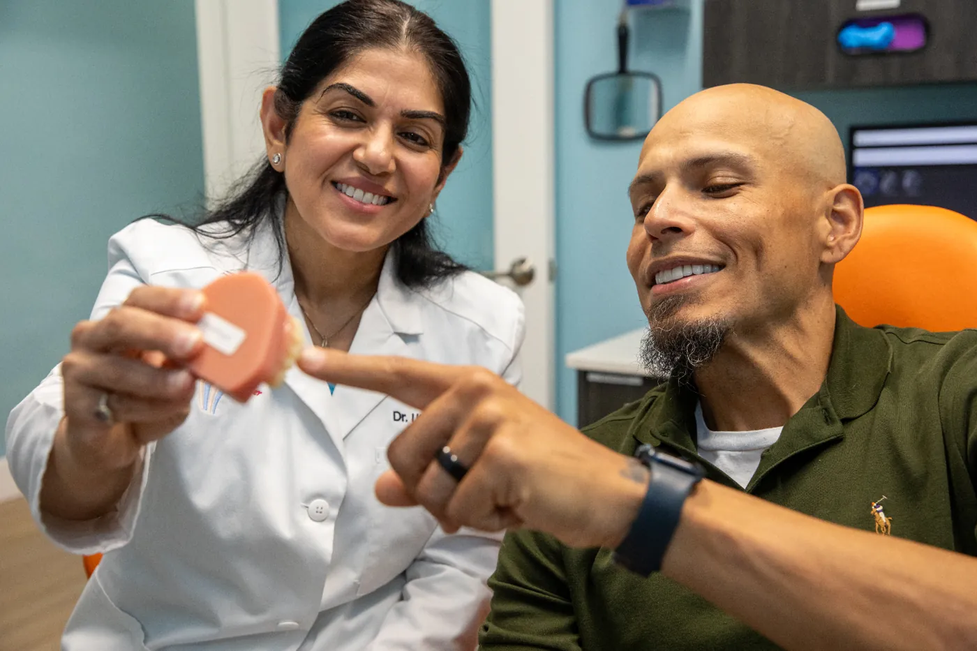 Dr. Uttma Dham showing a patient their new smile
